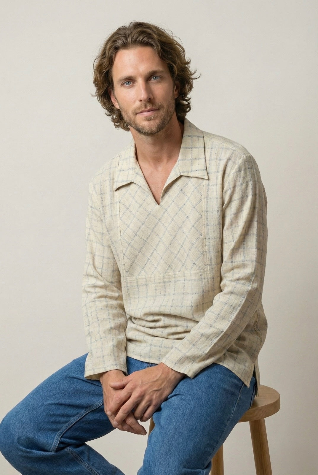 “Beige handcrafted checked shirt shown in a relaxed seated pose.