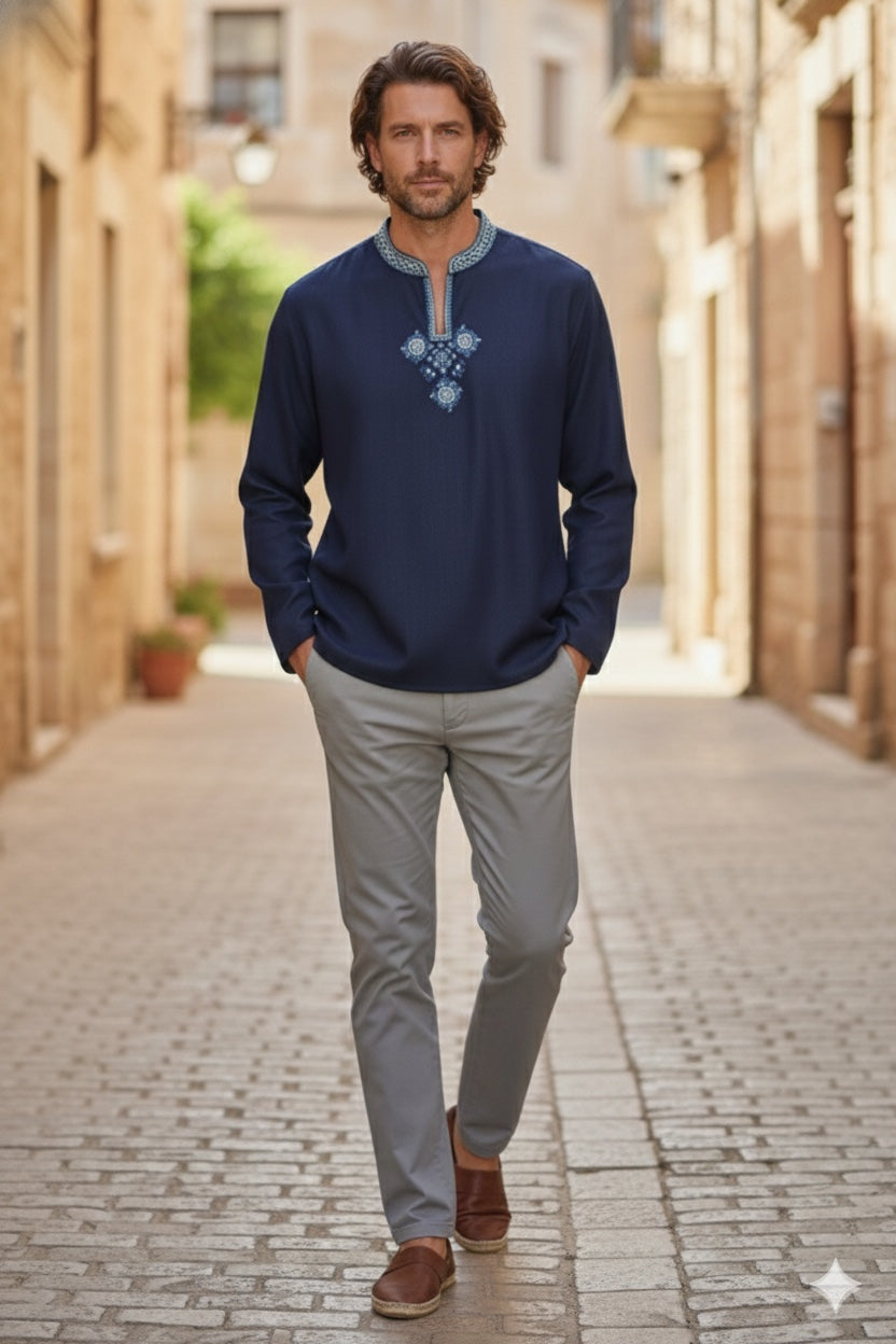 Man wearing a navy embroidered kurta shirt with grey pants walking outdoors on a stone street